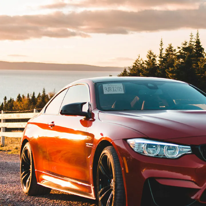 A red BMW M4 at sunset with a plate on the passenger visor.