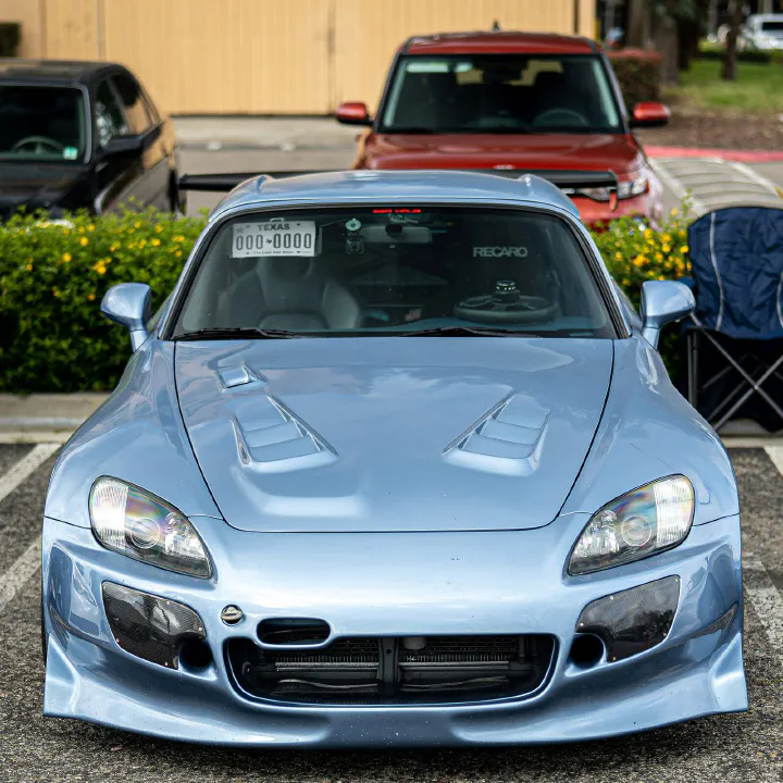 A silver-blue Honda S2000 with a plate on the visor.